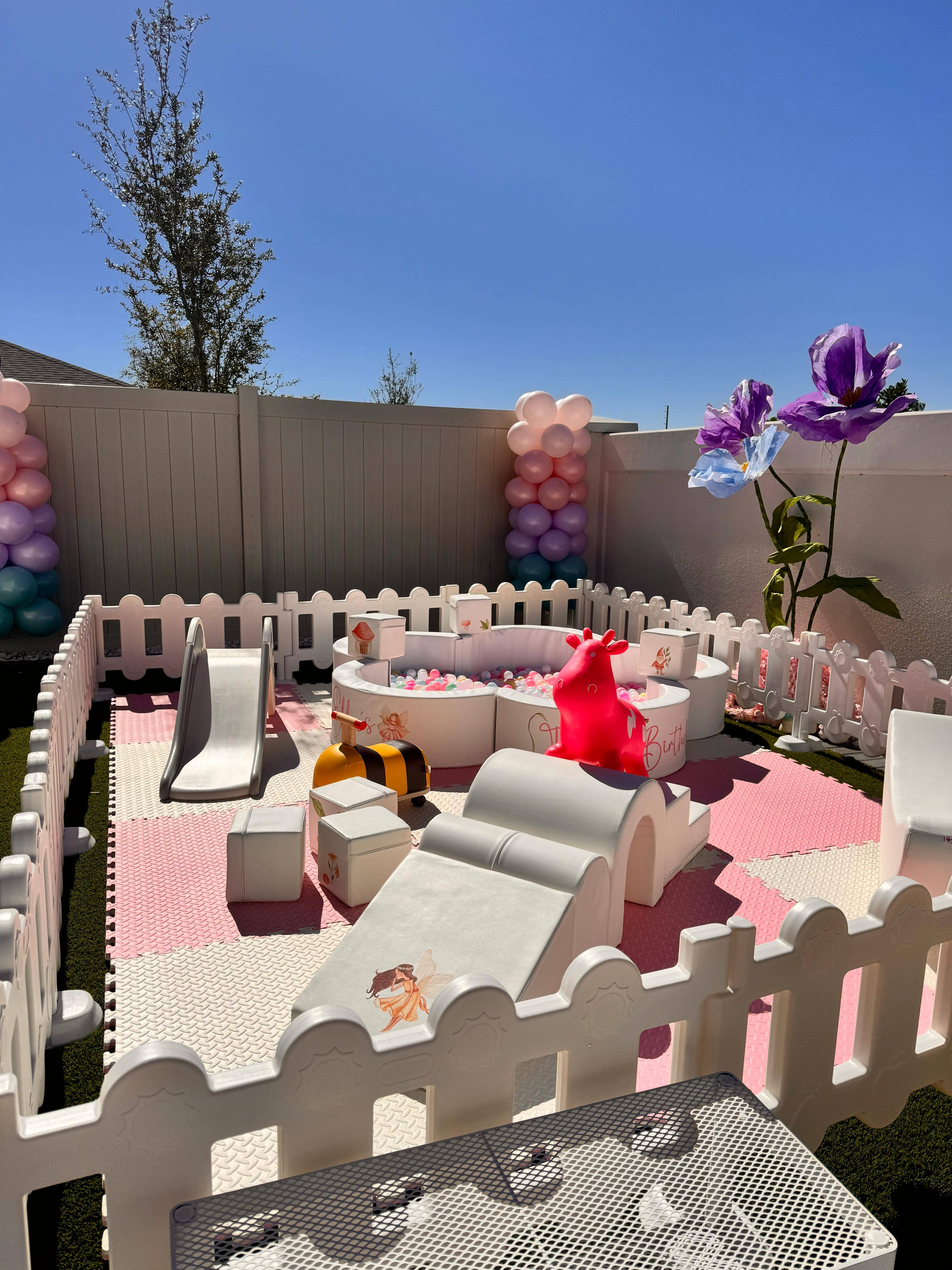 Full outdoor view of Blush and Bloom soft play rental — pink foam mats, flower-themed ball pit, soft climbers and pastel balloon column