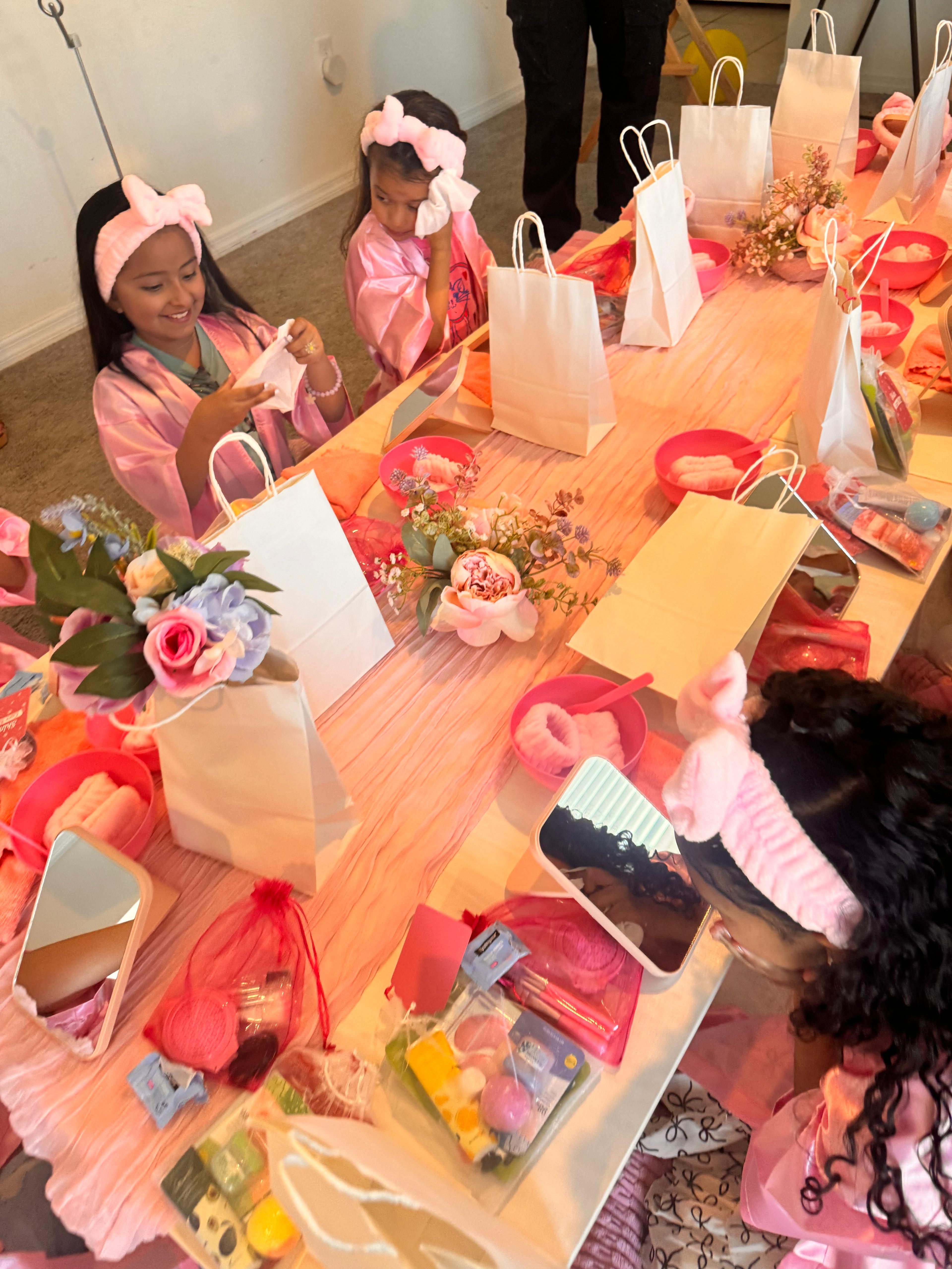 Girls in pink spa robes opening gift bags and doing spa activities at a Sparkle Spa kids party by Titi's Adventure