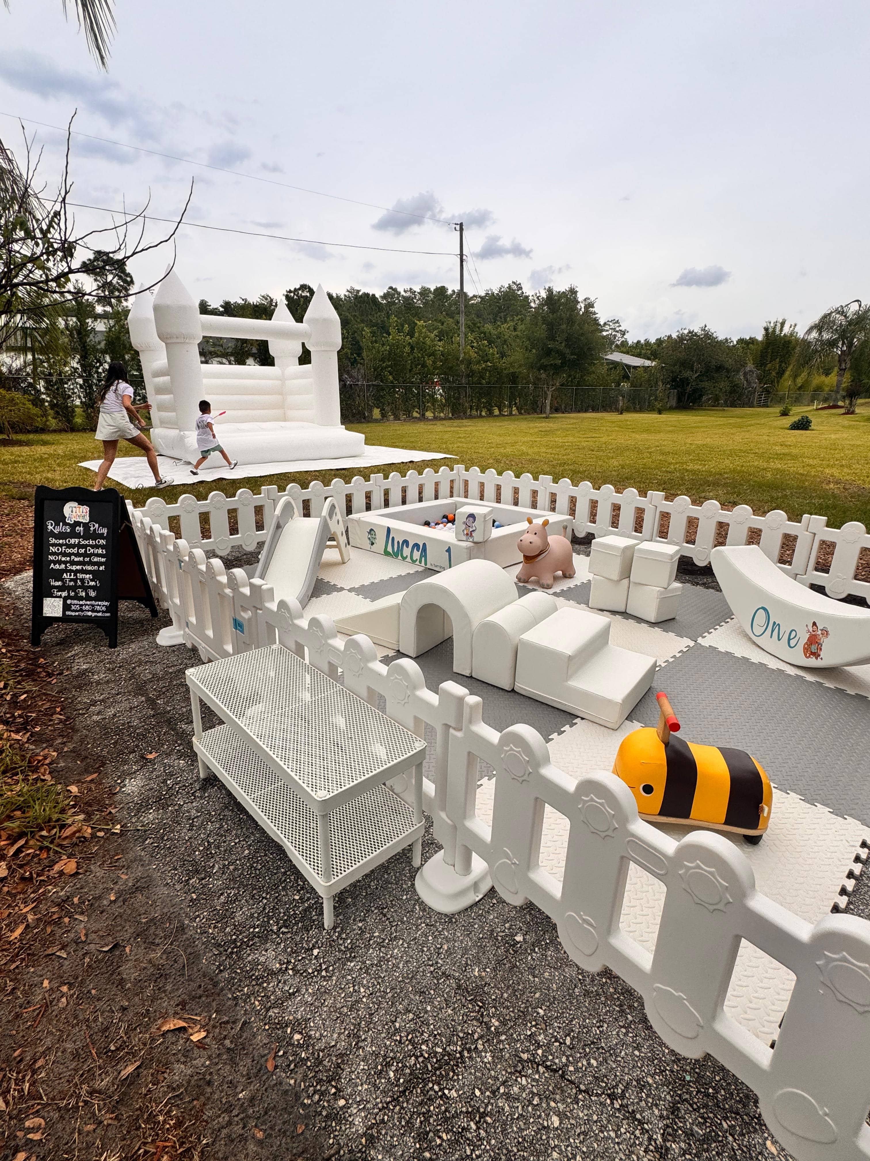 White castle bounce house with soft play setup on a sunny outdoor lawn